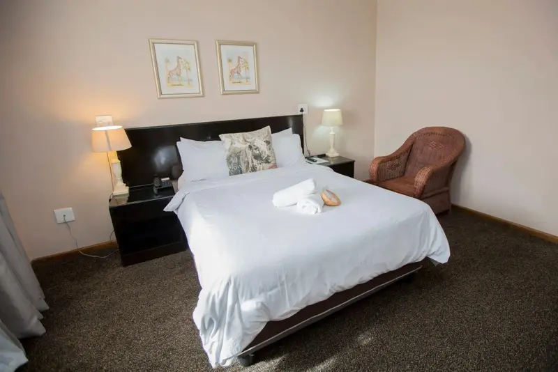 Une chambre lumineuse avec un grand lit recouvert d'une courtepointe blanche et d'oreillers.