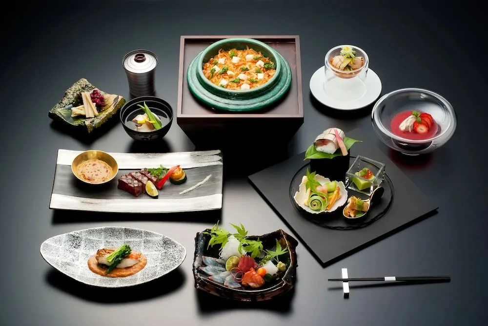 Présentation raffinée de plusieurs plats japonais sur fond noir.