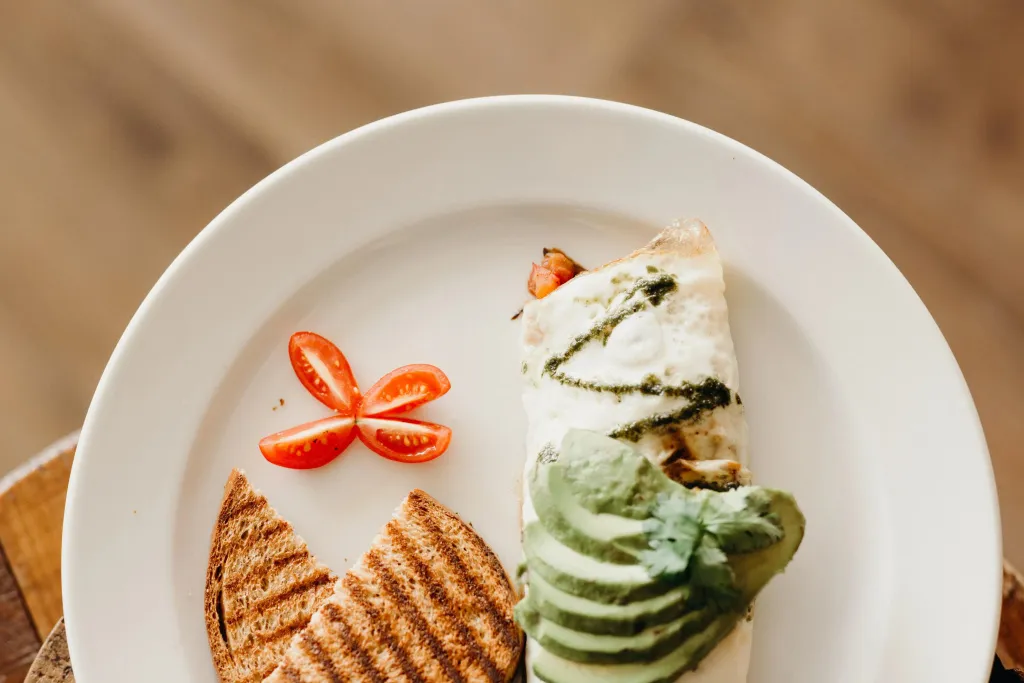 Assiette garnie d'une omelette, d'avocat, de tomates et de pain grillé.