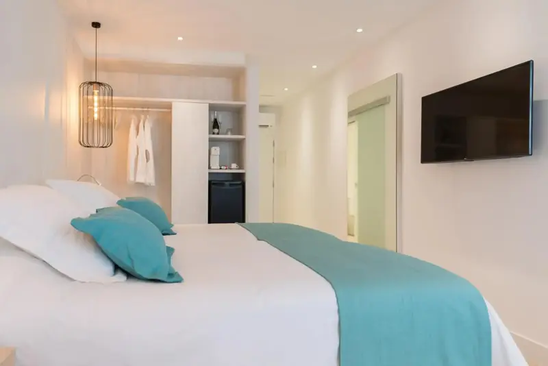 Une chambre lumineuse avec un grand lit recouvert d'une courtepointe turquoise.