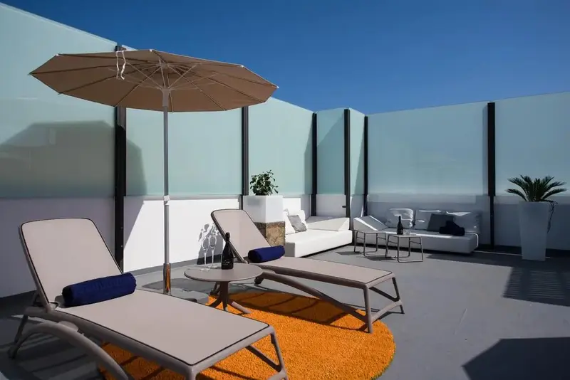 Terrasse aménagée avec des chaises longues et des canapés blancs.