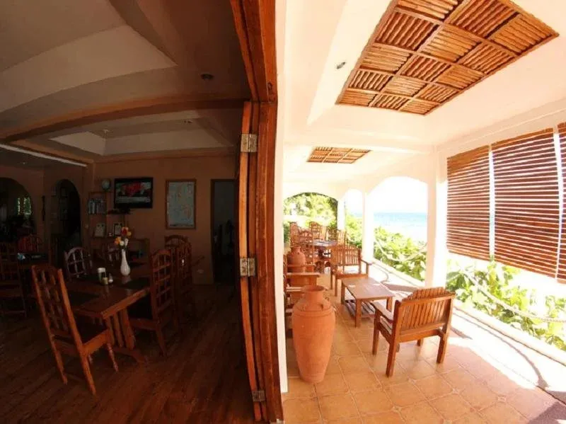 Une salle à manger s'ouvre sur une terrasse ombragée avec vue sur la végétation.