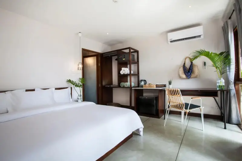 Une chambre lumineuse avec un grand lit et un espace bureau.