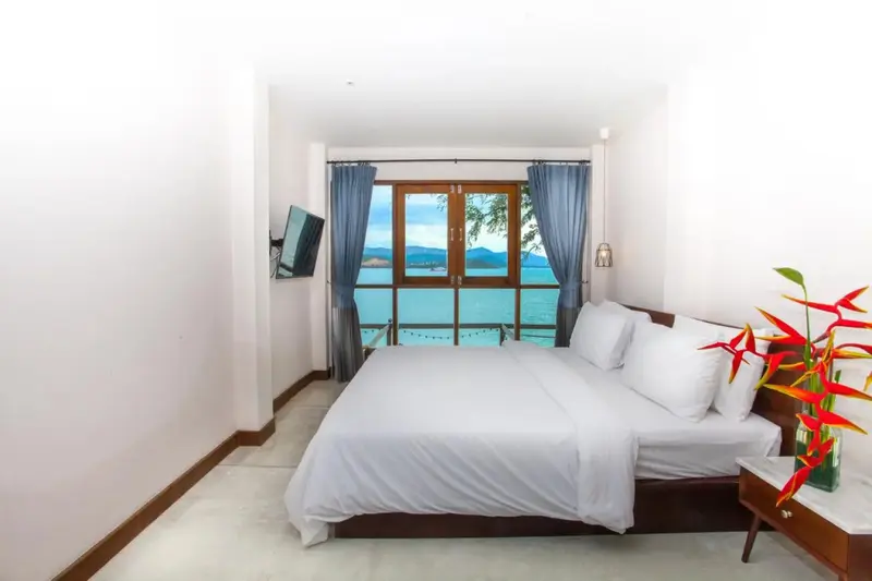 Une chambre lumineuse avec un grand lit face à une vue sur la mer.