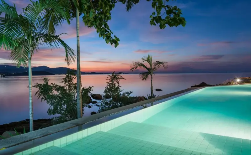 Une piscine à débordement offre une vue sur la mer au coucher du soleil.
