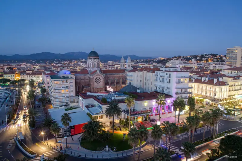 Vue aérienne d'une ville côtière illuminée au crépuscule.