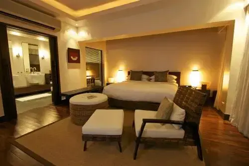 Une chambre lumineuse avec un grand lit et un espace salon.