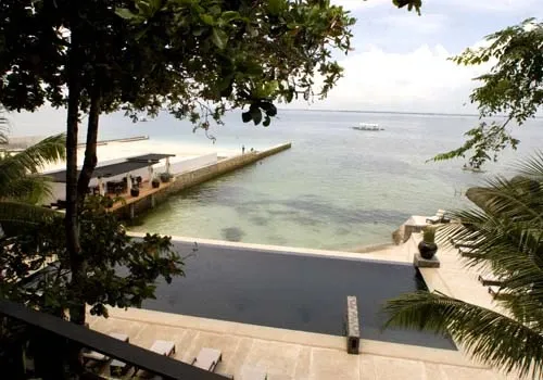 Une piscine à débordement surplombe la mer et un ponton.