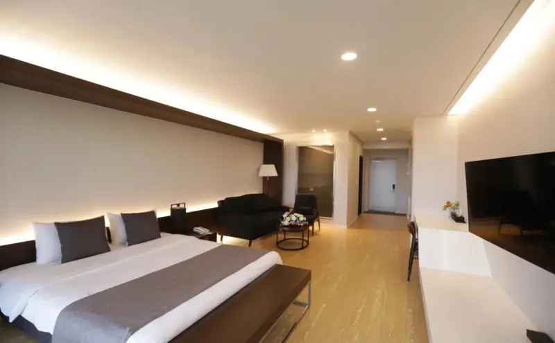 Une chambre lumineuse avec un grand lit et un espace salon.