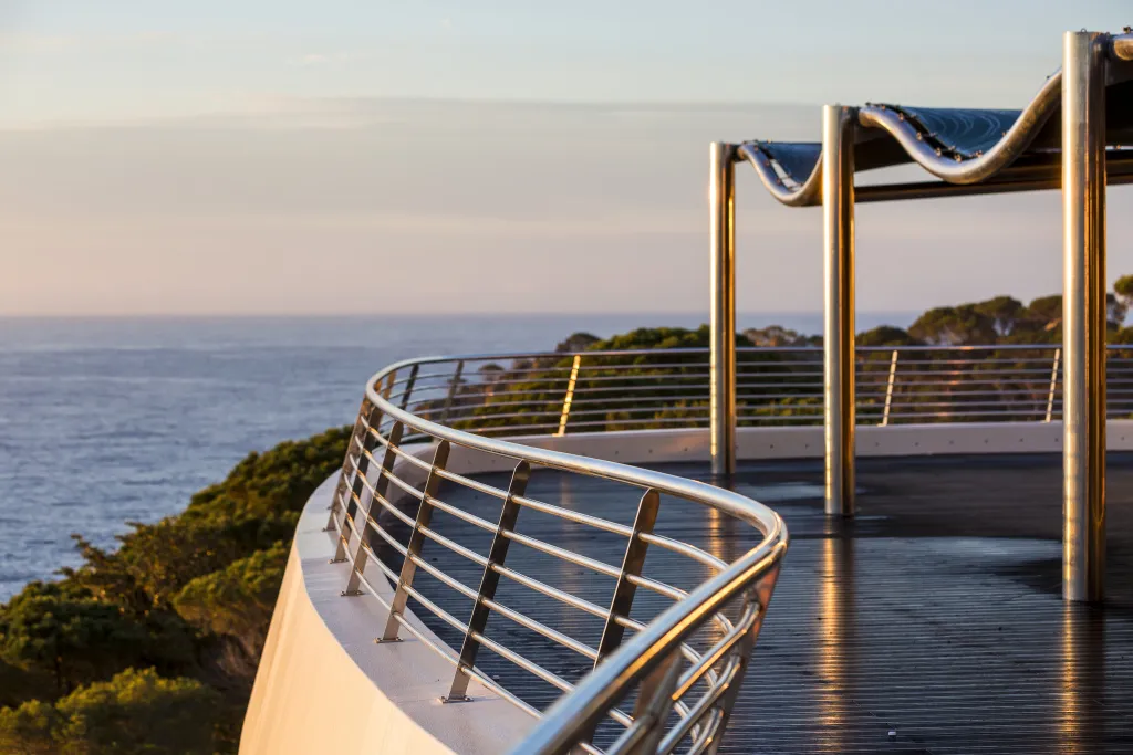 Terrasse en bois avec garde-corps métallique surplombant la mer.