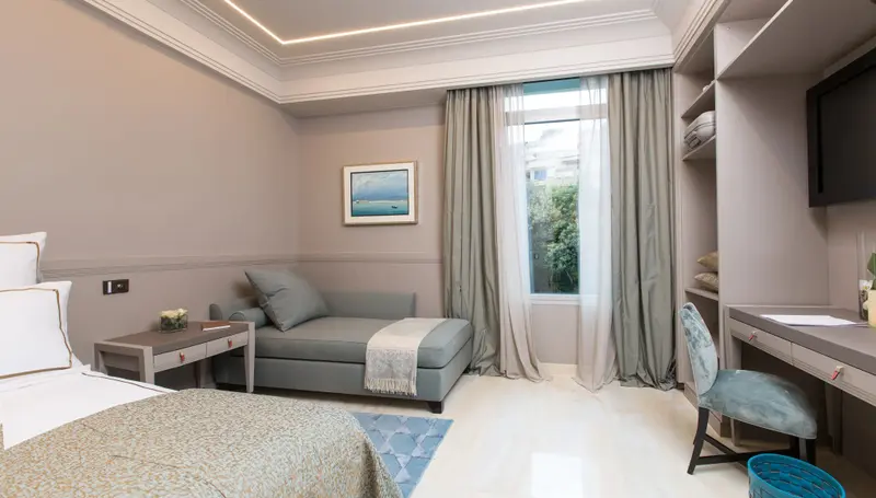 Une chambre lumineuse avec un lit, une chaise longue et un bureau.
