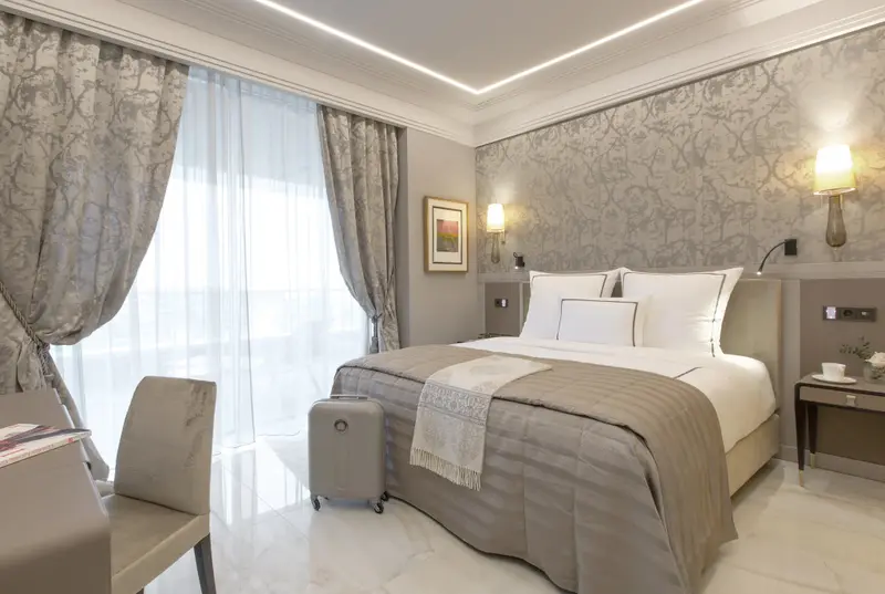 Une chambre lumineuse avec un grand lit et une fenêtre drapée.