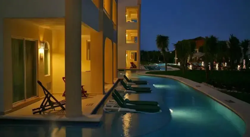 Transats alignés au bord d'une piscine illuminée en soirée.