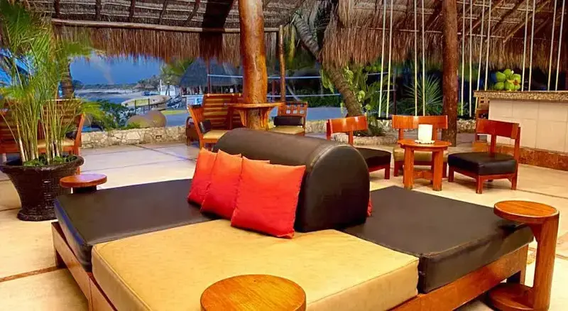Espace de détente extérieur avec mobilier confortable et végétation tropicale.