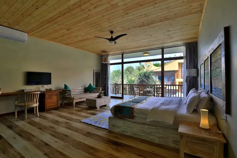 Une chambre spacieuse avec un lit king-size et un espace salon ouvert sur une terrasse.