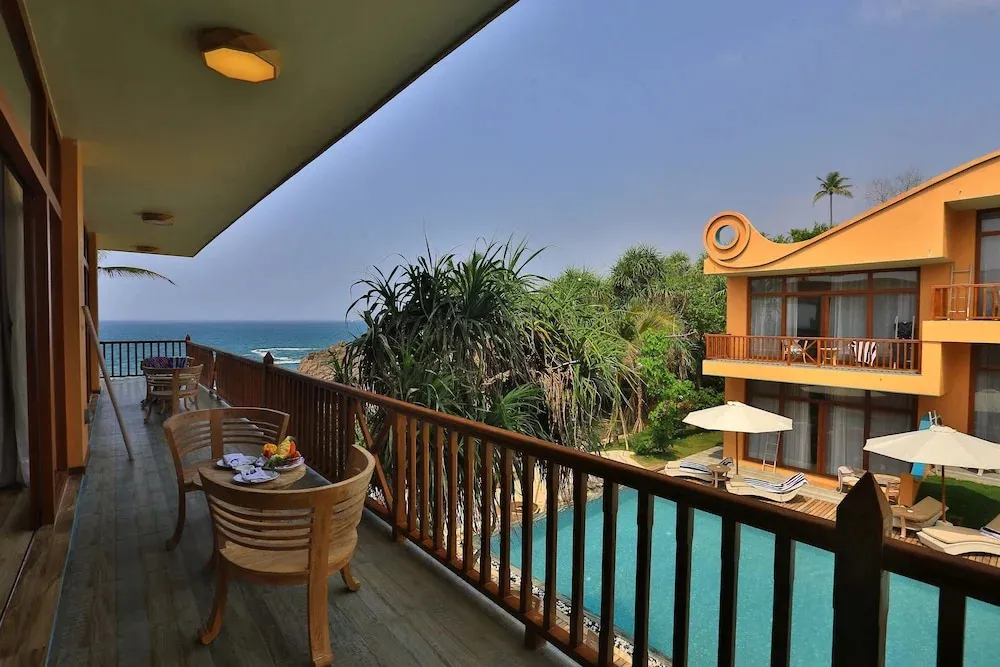 Une terrasse en bois offre une vue sur la mer et une piscine.