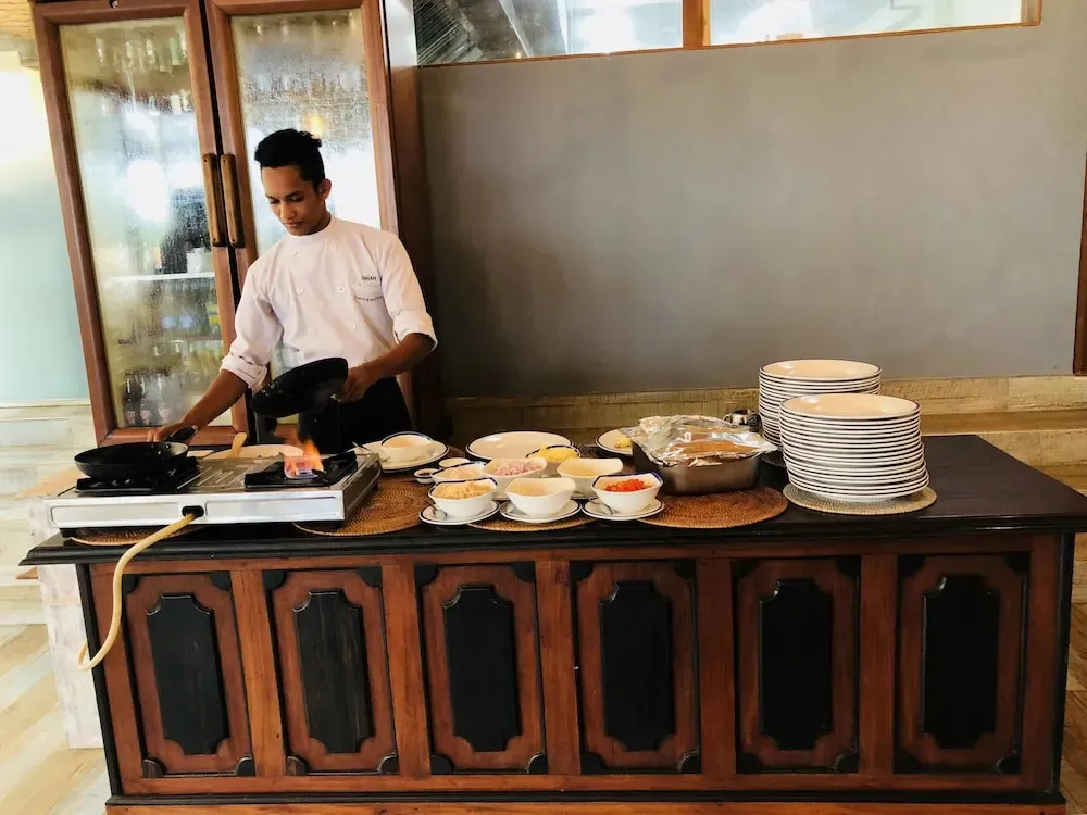 Un chef prépare des plats sur une plaque de cuisson devant un comptoir.