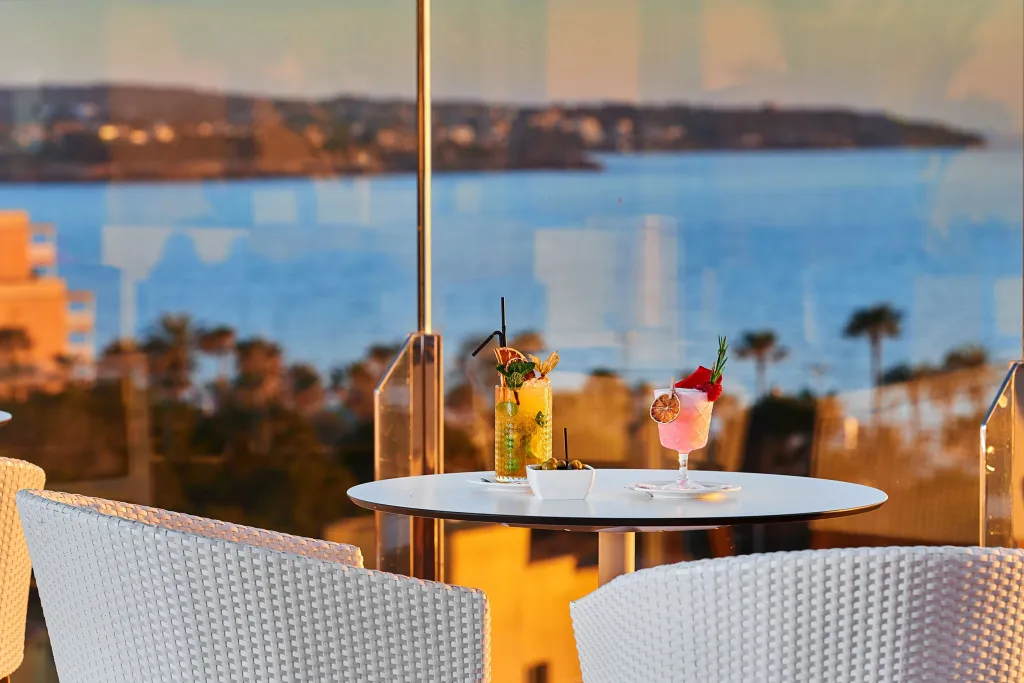 Deux cocktails colorés sont servis sur une table ronde face à la mer.