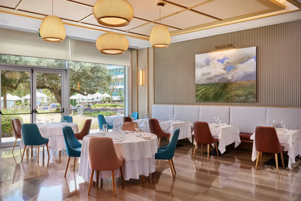Une salle lumineuse avec des tables dressées pour un repas.