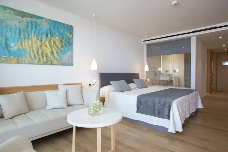 Une chambre lumineuse avec un canapé et un lit fait.