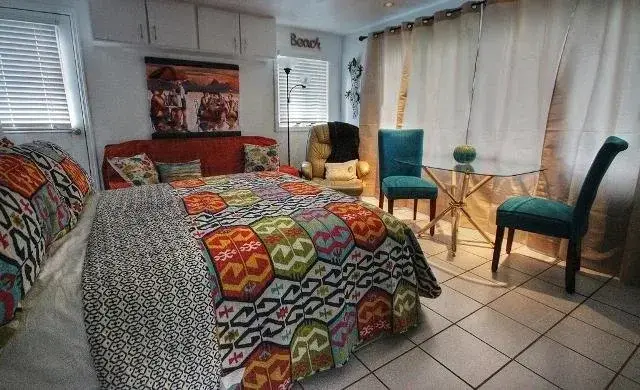 Une chambre colorée avec un lit recouvert d'une courtepointe et deux chaises près d'une petite table.