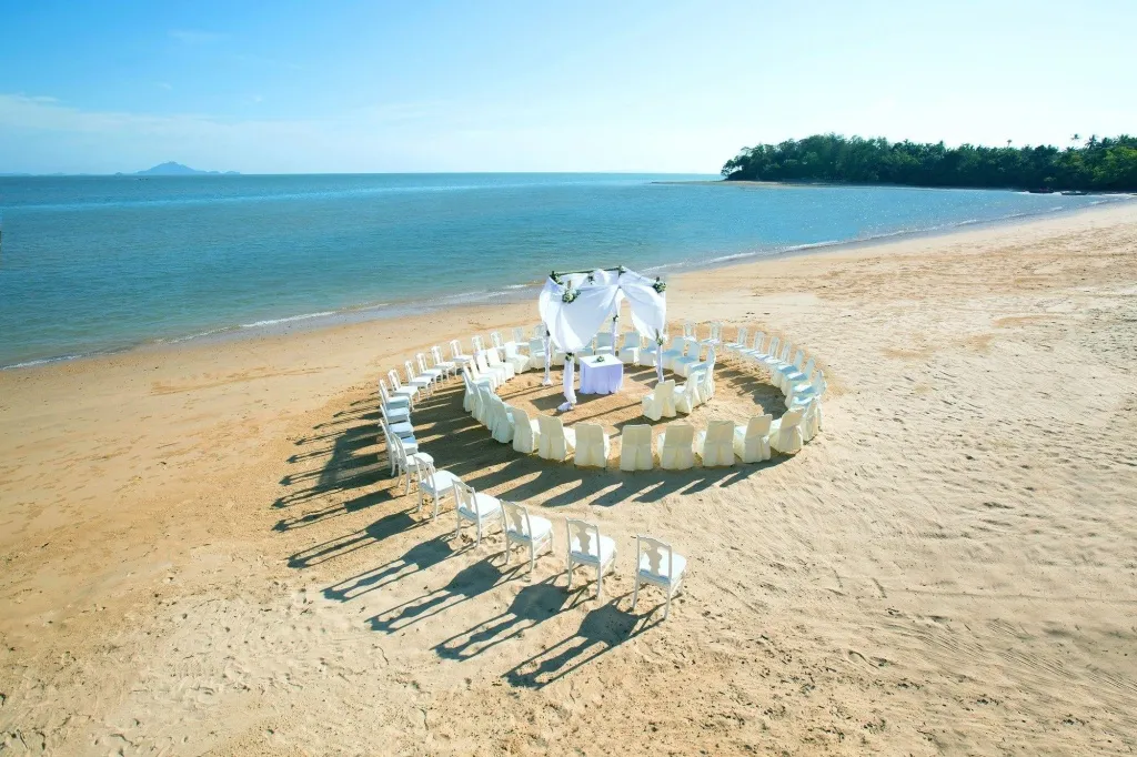 Une cérémonie de mariage est mise en place sur une plage de sable fin face à la mer.