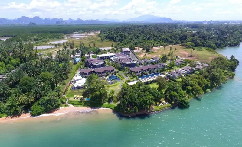 Vue aérienne d'un complexe hôtelier bordant une plage et une végétation luxuriante.