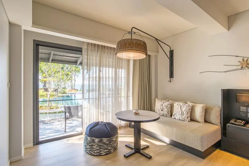 Espace de détente lumineux avec canapé et accès à une terrasse.
