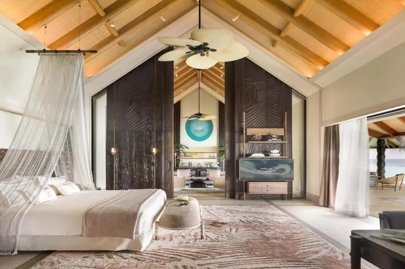 Une chambre spacieuse avec un lit à baldaquin et un accès à une vue sur l'océan.