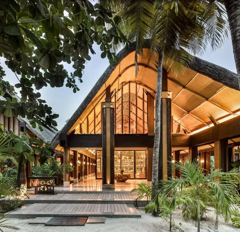 Entree d'un batiment avec une architecture en bois et une vegetation luxuriante.