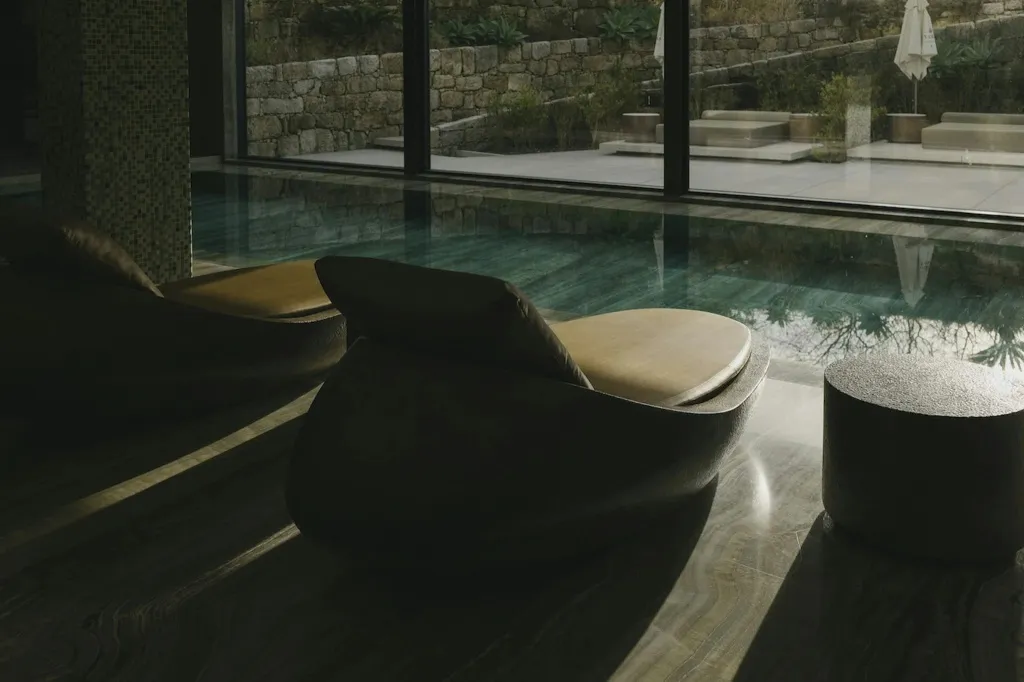 Transats et table basse au bord d'une piscine intérieure.