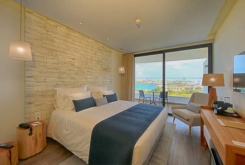 Une chambre lumineuse avec un grand lit donnant sur une vue mer.