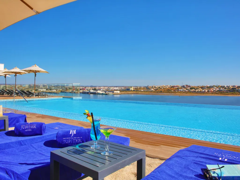 Transats bleus et cocktails rafraîchissants au bord d'une piscine à débordement.