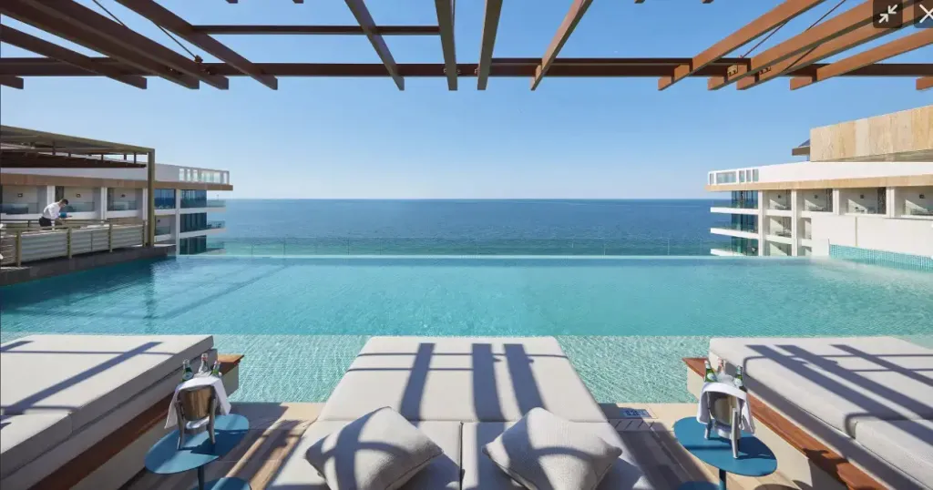 Transats alignés au bord d'une piscine à débordement avec vue sur la mer.