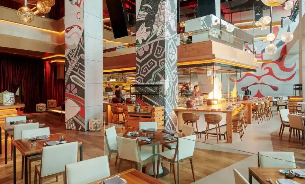 Une salle de restaurant lumineuse avec des tables dressées et un comptoir de bar.