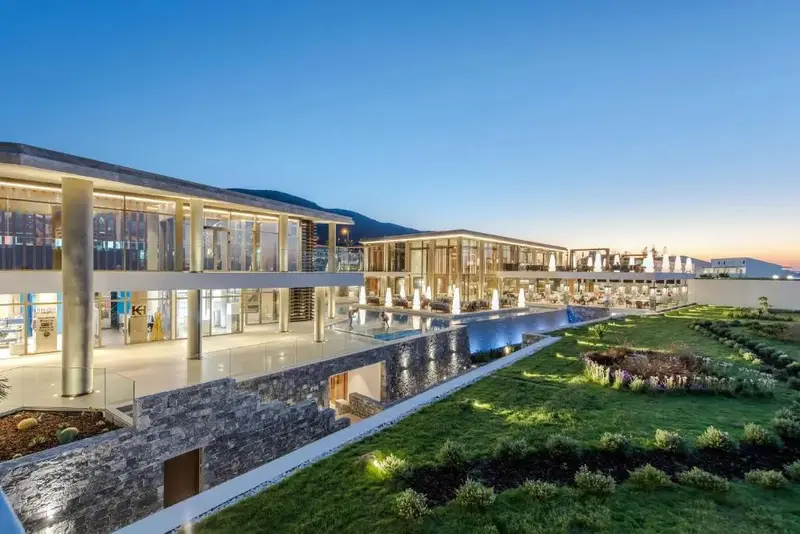 Architecture moderne d'un bâtiment avec une piscine et un jardin verdoyant au crépuscule.