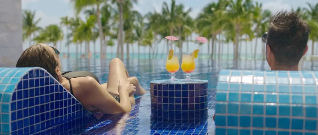 Deux personnes se détendent dans une piscine avec des cocktails.