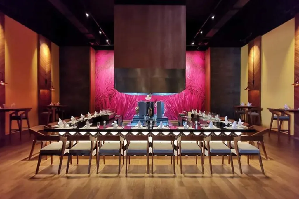 Une longue table est dressée dans une salle à manger élégante avec un chef cuisinant au centre.