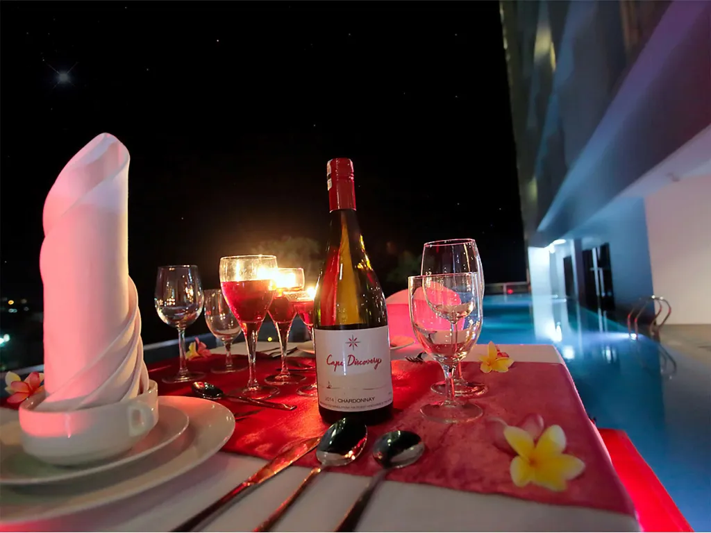 Une table dressée avec une bouteille de vin et des verres à vin, décorée de fleurs.