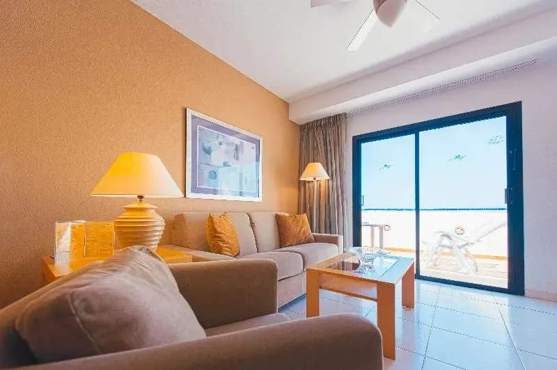 Un espace de détente intérieur avec canapés et une vue sur une terrasse ensoleillée.