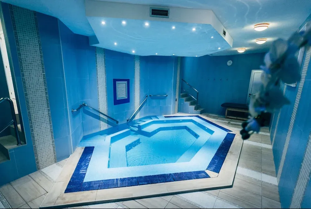Un espace de détente intérieur avec une piscine à débordement et des mosaïques bleues.