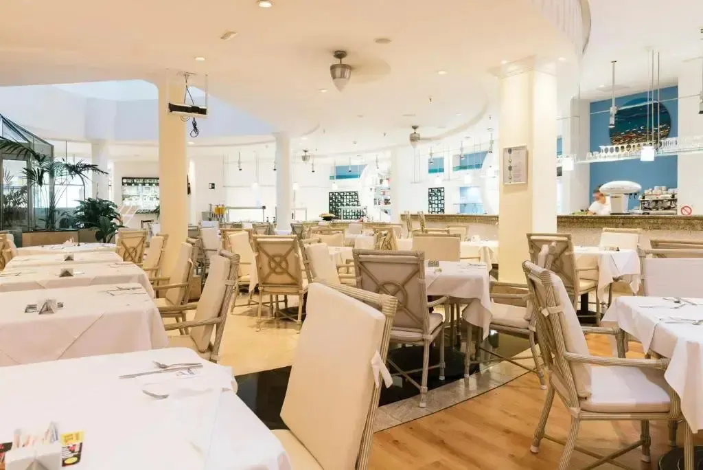 Une salle lumineuse avec des tables dressées pour le service.