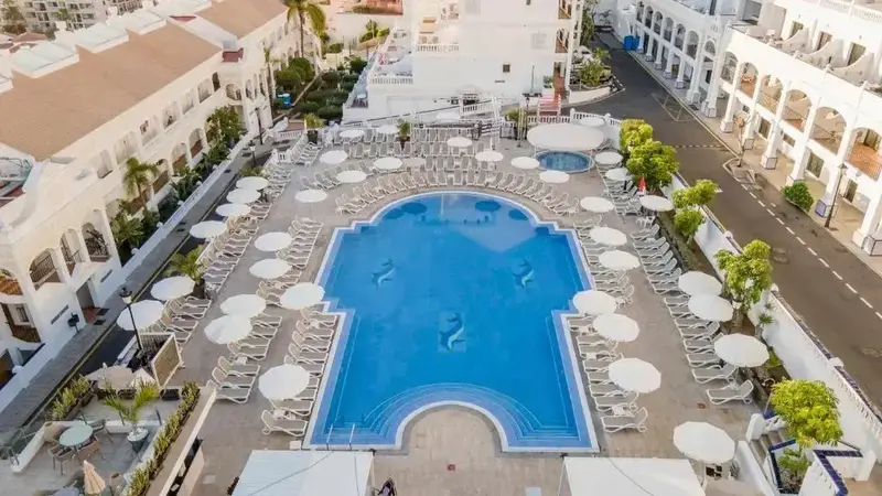 Vue aérienne d'une piscine entourée de transats et de parasols.