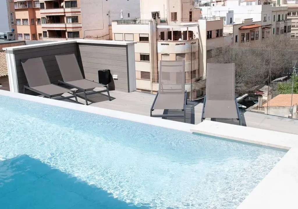 Transats et piscine sur une terrasse ensoleillée.