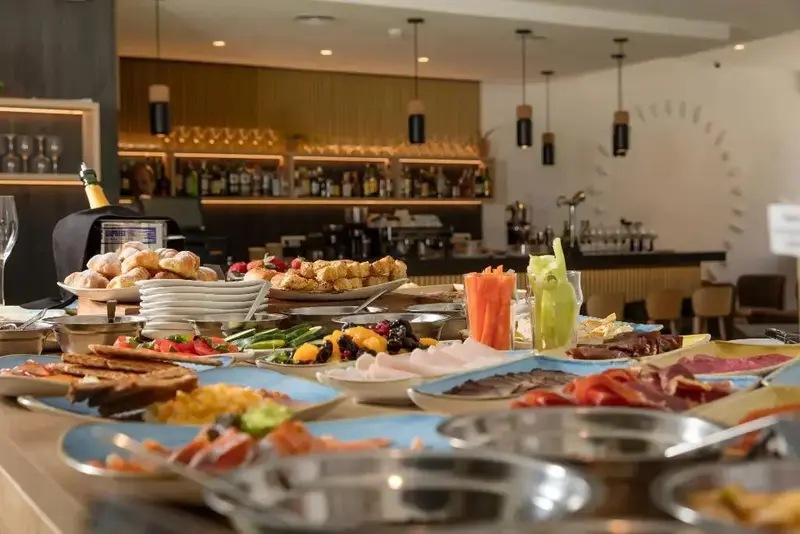 Un buffet propose une grande variété de plats et de boissons dans une salle lumineuse.
