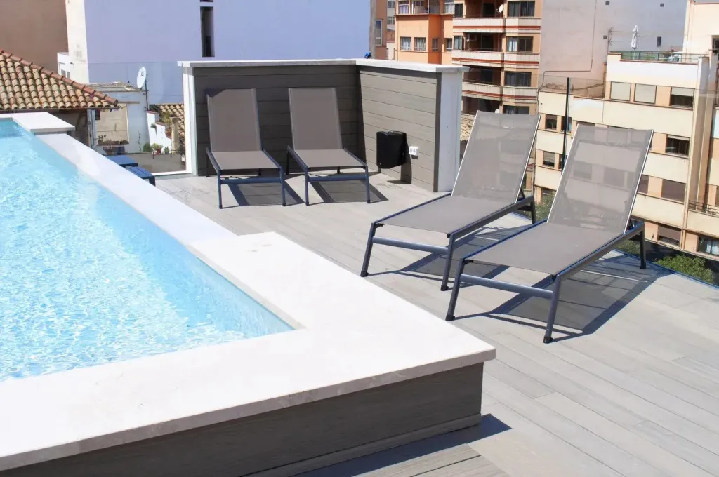 Transats et piscine sur une terrasse ensoleillée.