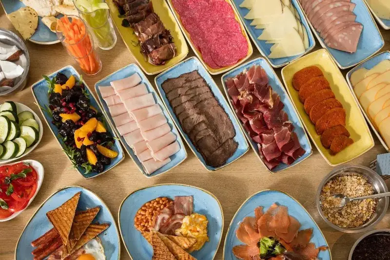 Assortiment de charcuteries, fromages et crudités disposés sur des plats.