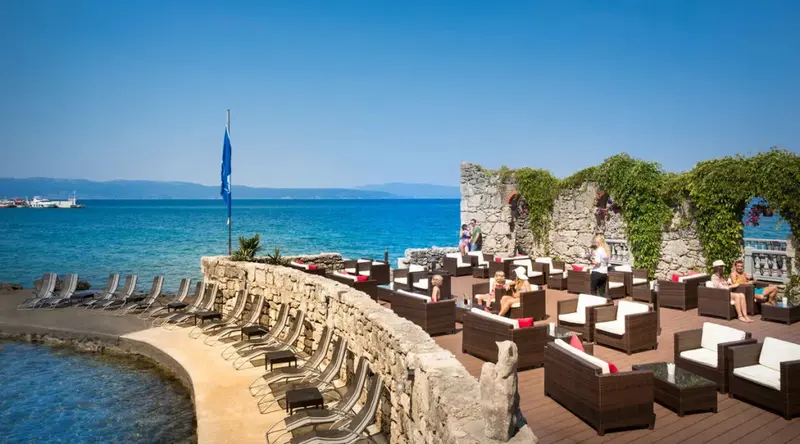 Terrasse aménagée avec mobilier de jardin et transats au bord de la mer.