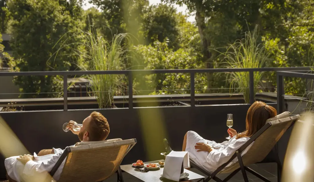Deux personnes se détendent sur une terrasse ensoleillée avec des boissons et des collations.