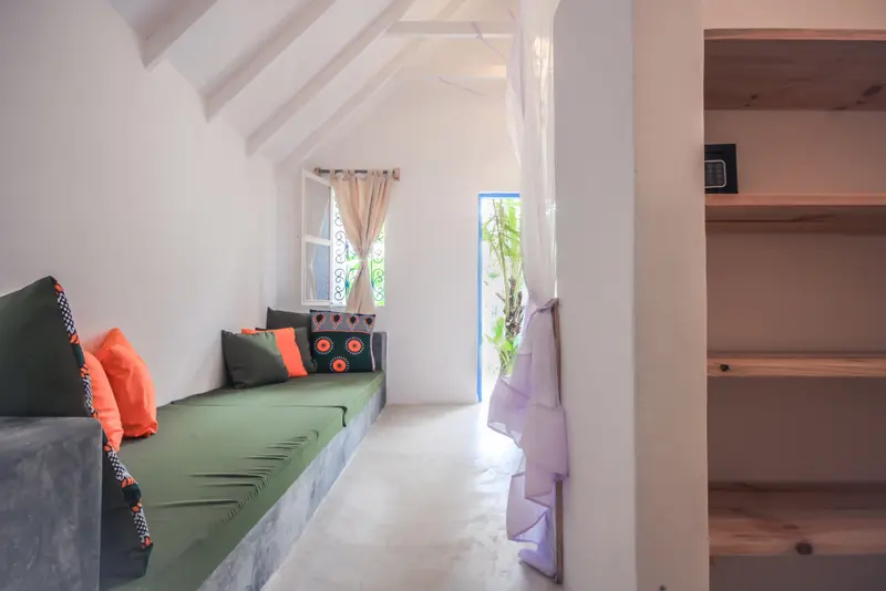 Espace de détente intérieur avec coussins colorés et fenêtre lumineuse.